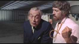 James Coburn commiserates with a visibly nauseous John Huston.