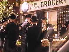 ‘Jewish’ music kicks in, as we obverse the people in their funny clothes.